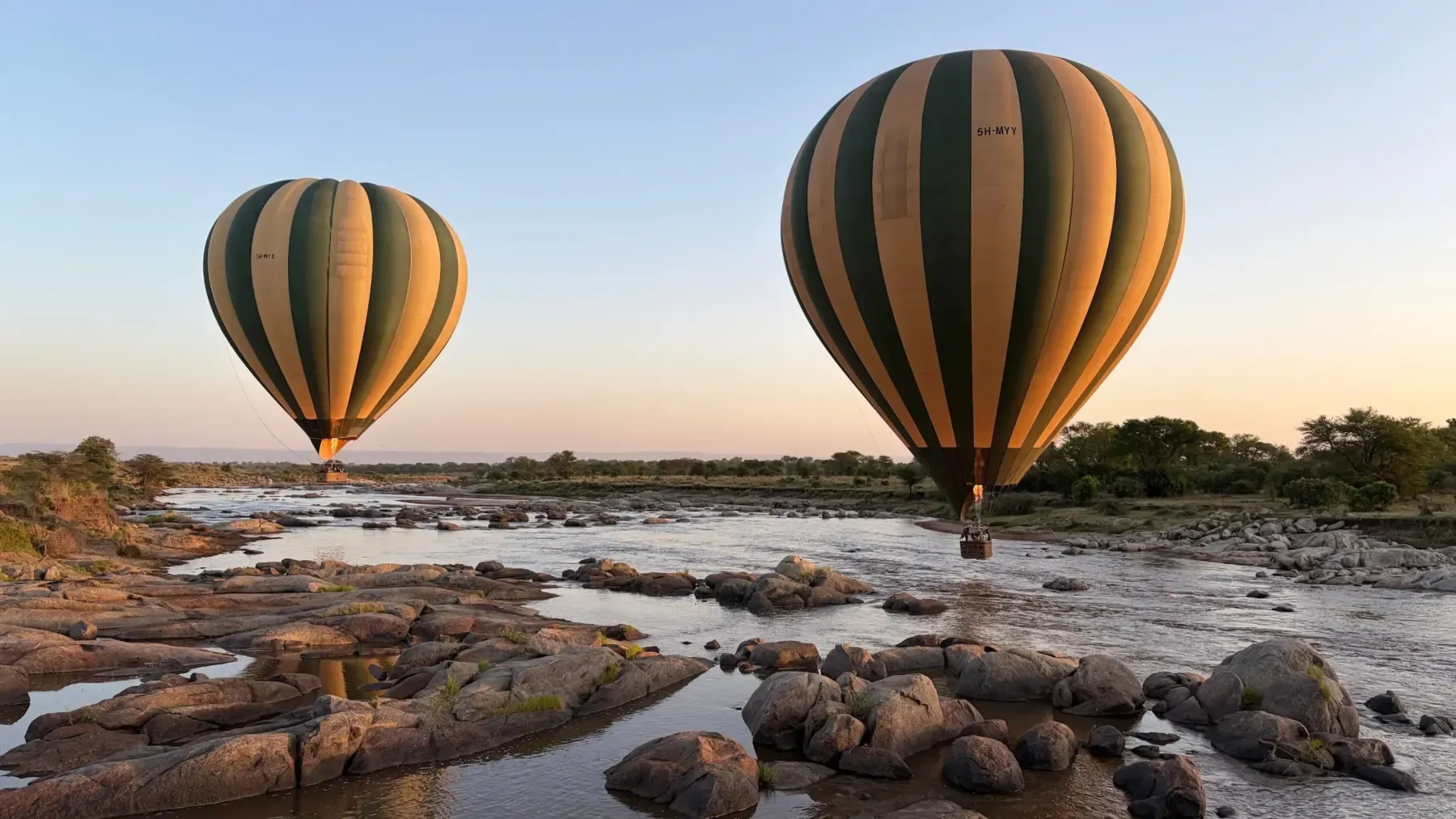 Mongolfiere in volo all'alba sopra un fiume del Serengeti, Tanzania