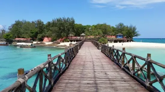 Passerella in legno verso l'isola di Prison Island con capanne e spiaggia bianca